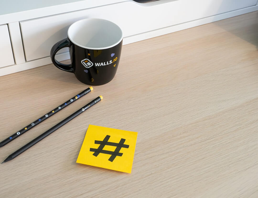 a cup of coffee, pencils, and a yellow sticker on a table