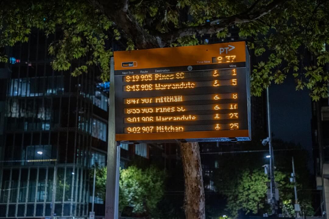 Bus schedule at night shows upcoming arrivals.