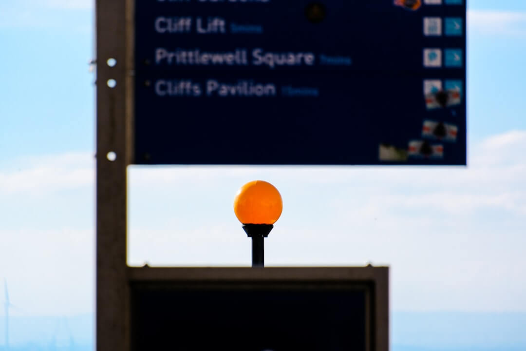 A street sign with an orange ball on top of it