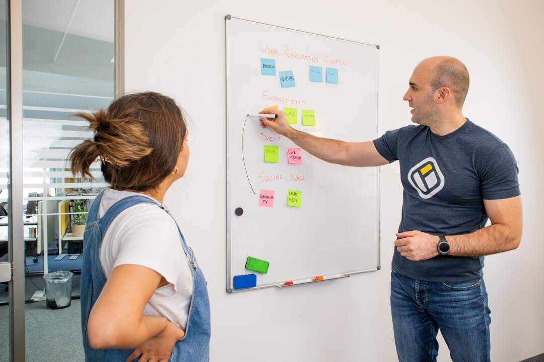 a man and a woman standing in front of a white board