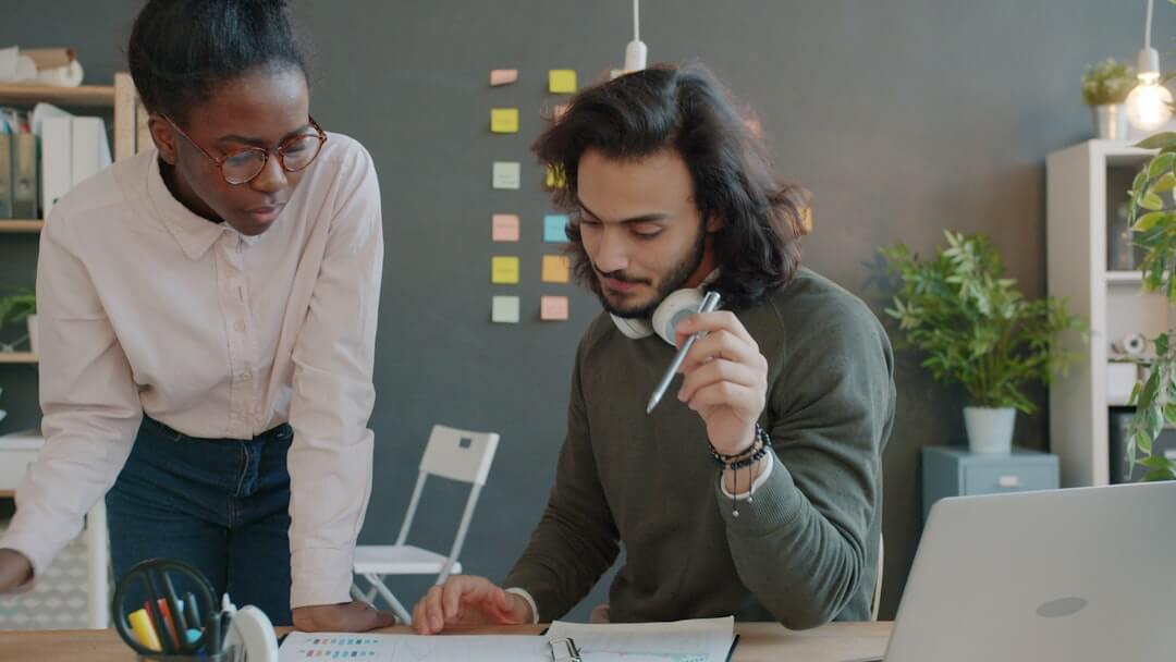 Two colleagues collaborating at a desk in an office.