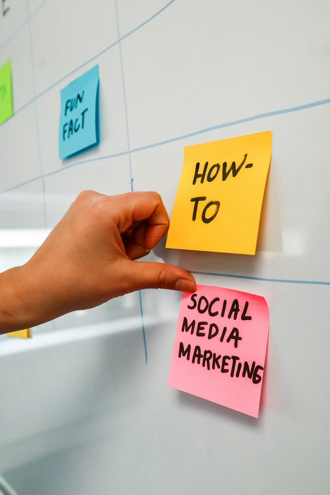 a hand is pointing to sticky notes on a bulletin board
