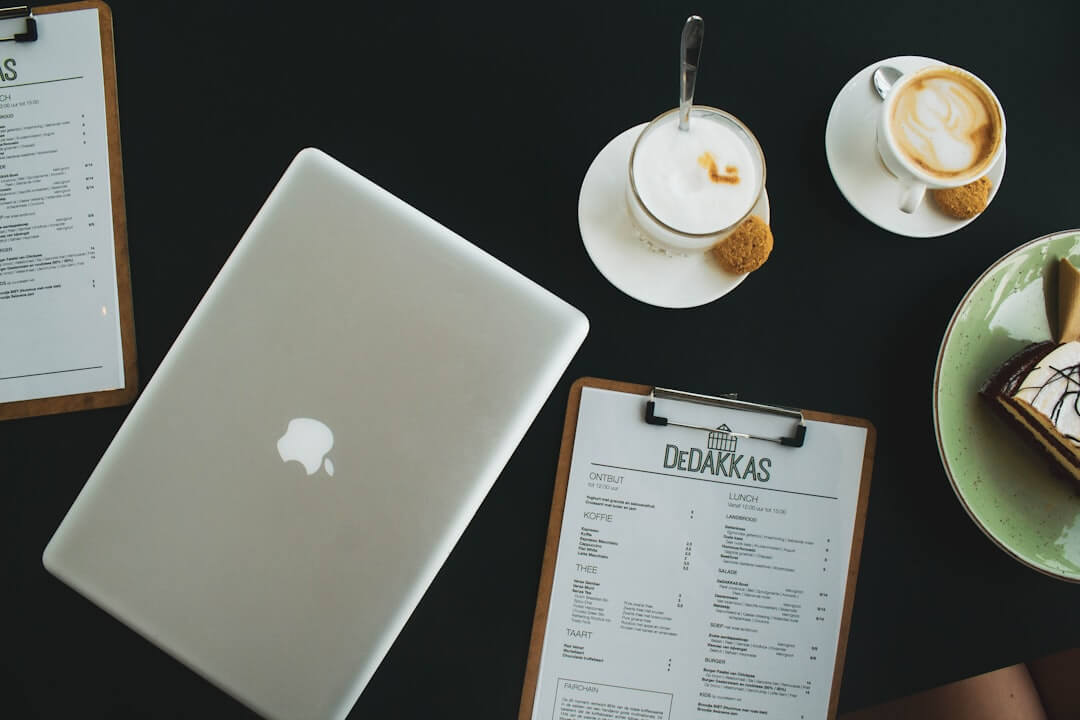 silver macbook beside white ceramic teacup on saucer