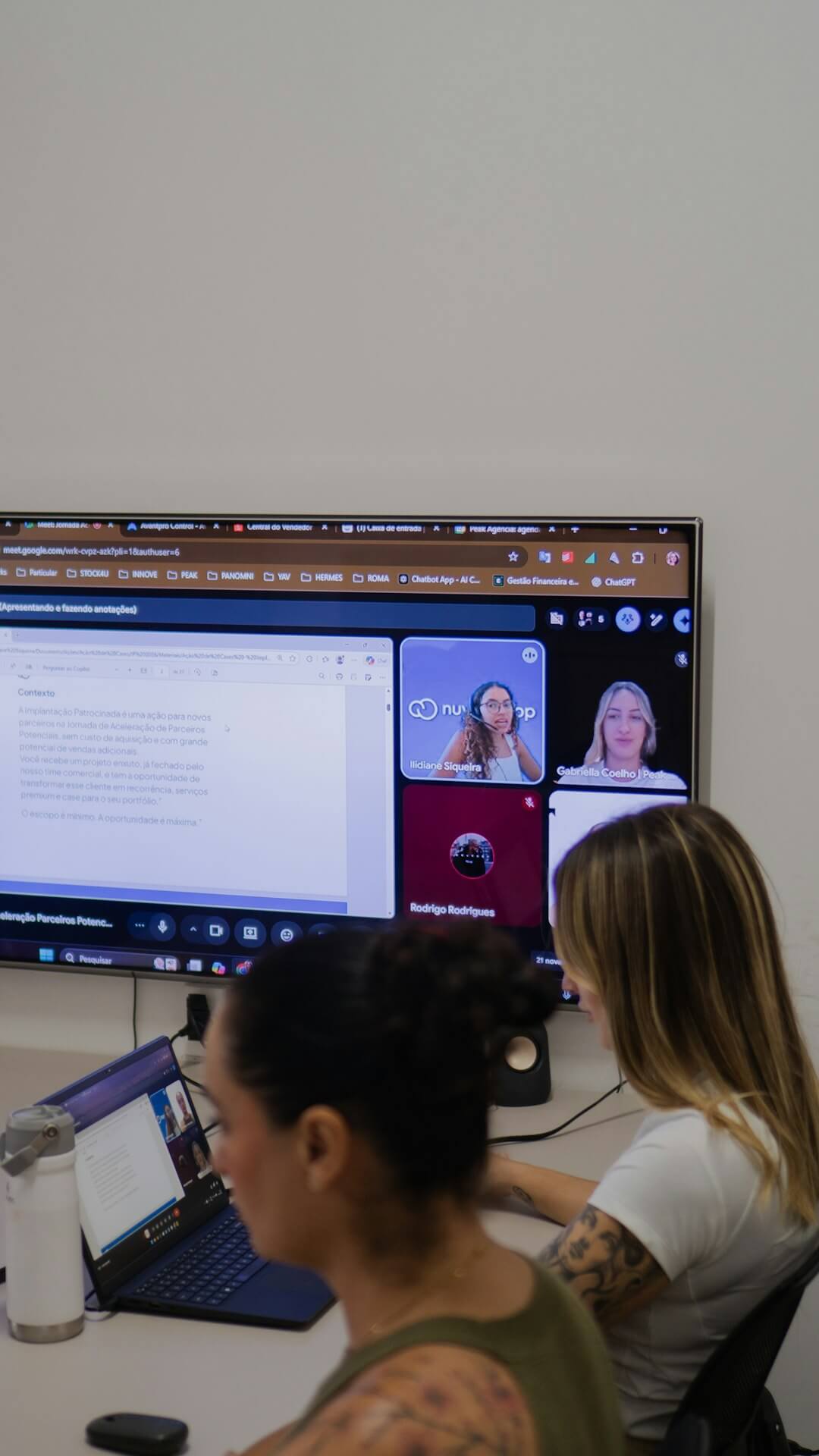 People in a video conference call on a large screen.