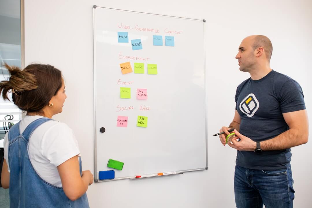 a man and a woman standing in front of a white board