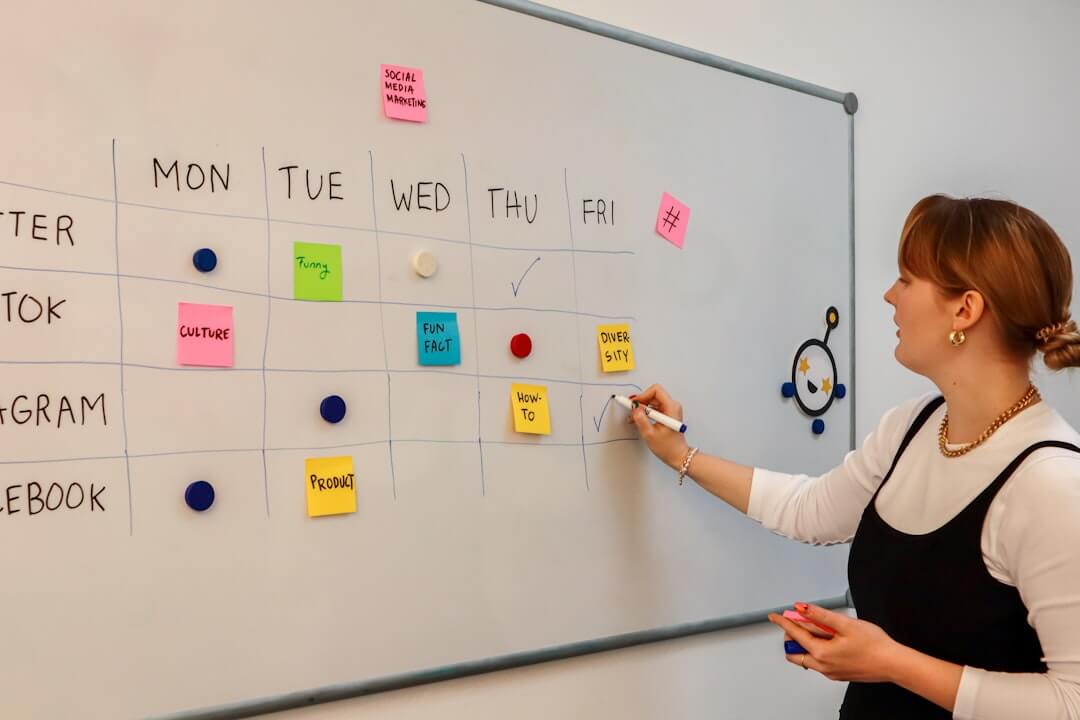 a woman writing on a white board with sticky notes