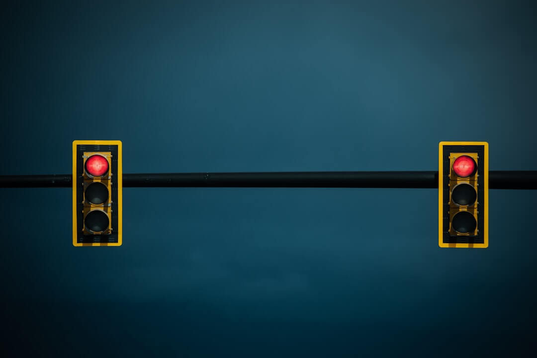 Two traffic lights on a black pole with a blue background