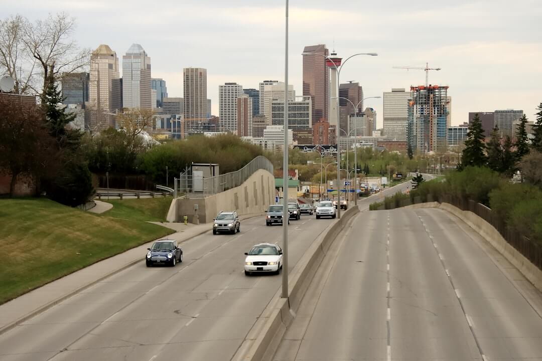 Cars driving on a highway towards a city skyline.