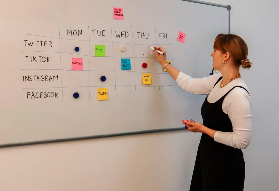 a woman writing on a white board with sticky notes