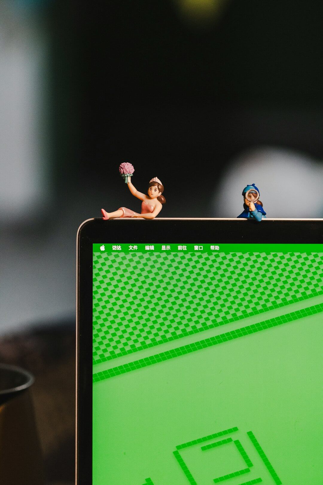 A computer screen with two small figurines sitting on top of it