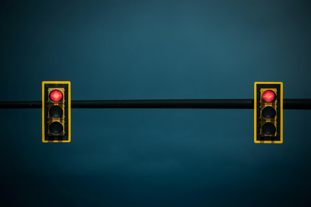 Two traffic lights on a black pole with a blue background