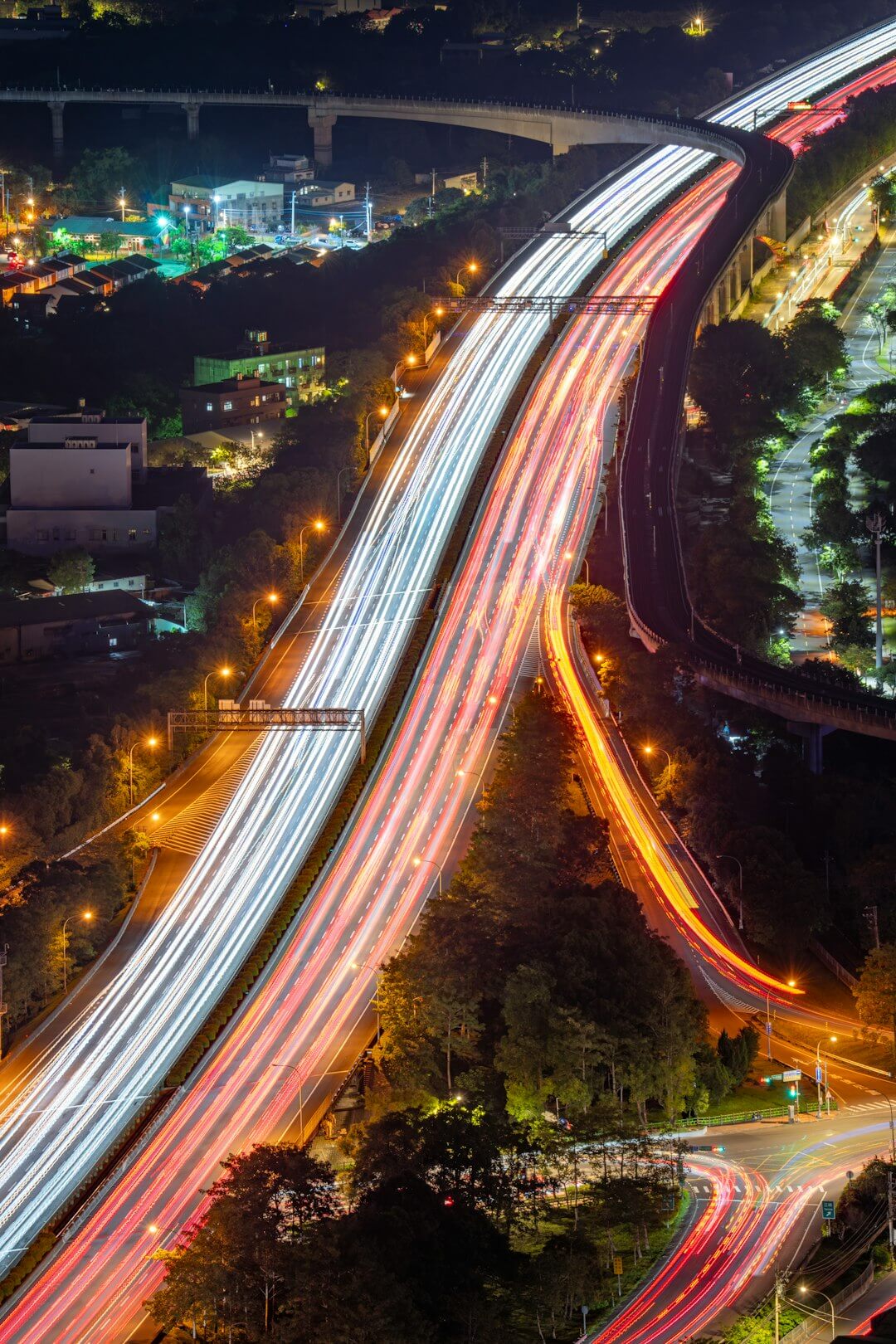 Highway traffic trails at night with city lights